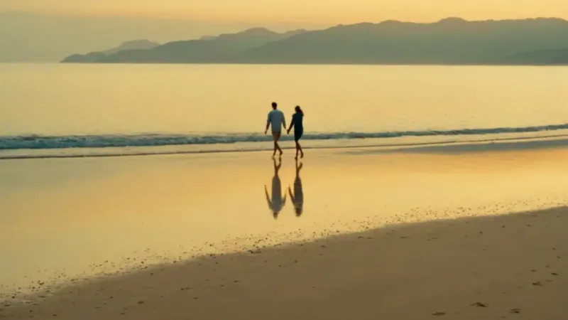 Una pareja pasea en la playa al atardecer