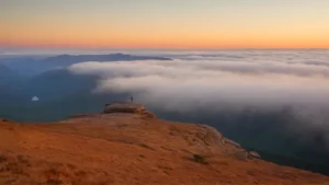 Una figura contempla el amanecer montañoso